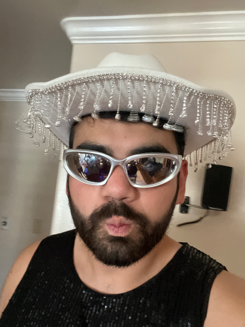 Jorge Santana in silver glasses and a white cowboy hat with beaded fringe.